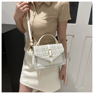 Detailed view of white tweed crossbody bag with gold hardware and leather strap