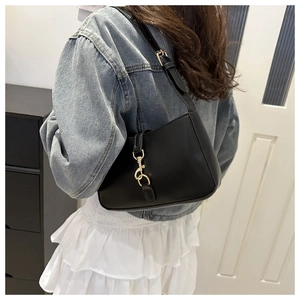 Detail of black leather underarm bag with gold lobster clasp and adjustable strap on model