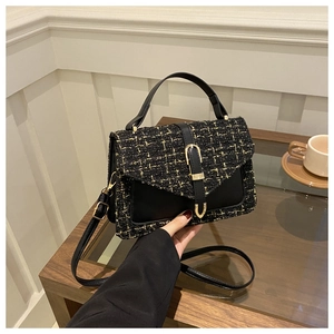 Detail of tweed crossbody bag with gold buckle on wooden surface in elegant setting