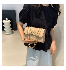 Close-up of beige quilted chain bag featuring a gold metal lock and faux leather texture