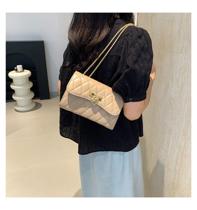 Beige quilted crossbody bag with gold chain strap shown on model in a modern interior