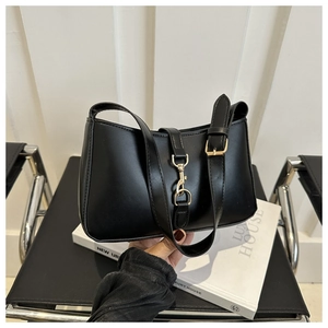 Detail of a minimalist black leather underarm bag featuring a elegant gold metal buckle