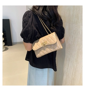 Detail of beige quilted shoulder bag with gold chain strap and flap closure on a model