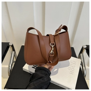 Detailed close-up of brown leather underarm bag with elegant metal buckle detail