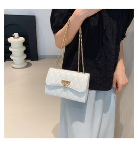 Detail of white quilted handbag featuring gold triangle lock and chain strap on a model