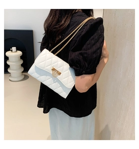 Side view of white quilted crossbody bag with gold chain strap on model's shoulder