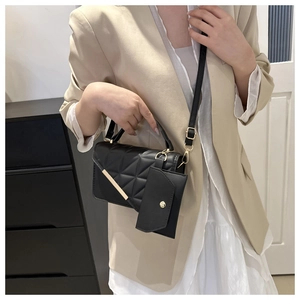 Detail of black quilted shoulder bag with gold metal trim and detachable pouch on model