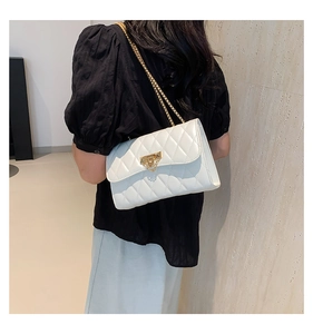 Quilted white crossbody bag with gold chain strap shown on a model's shoulder