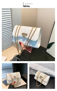 Detail of white quilted crossbody bag featuring golden chain and metal turn-lock closure