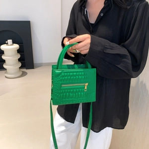 Vibrant green crocodile pattern handbag with gold zippers and matching shoulder strap