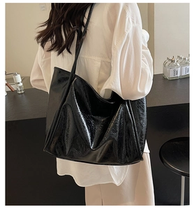 Detail of glossy black faux leather tote bag showing smooth texture and large capacity