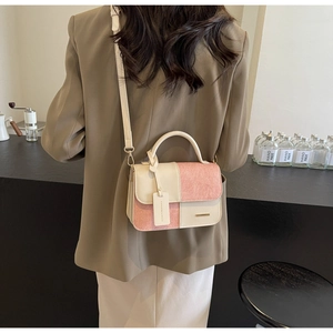 Detail of color-block tote bag with gold hardware on a model in minimalist attire