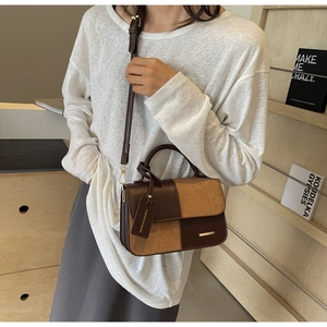 Detail of color-block leather and suede handbag showing golden hardware and tag