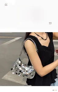 Detail of silver sequin shoulder bag with chain strap worn by model in casual street style