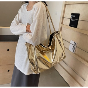Detailed view of large metallic gold tote bag showing mirror-like glossy finish and long straps