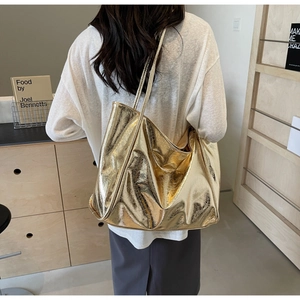 Detailed view of a gold metallic tote bag with wrinkled texture on a model's shoulder