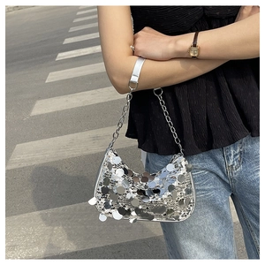 Silver sequin crescent shoulder bag with metallic chain strap shown in a street style view