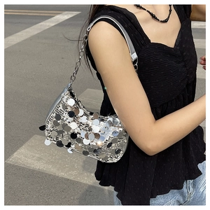 Borsa a spalla con paillettes argento e catena metallica in un contesto urbano
