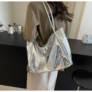 Detailed view of silver metallic tote bag with pleated texture on model shoulder