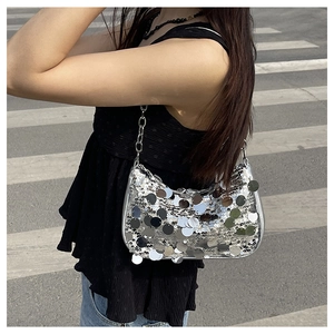 Dettaglio della borsa hobo con paillettes argento e tracolla a catena indossata da una donna