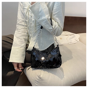 Dettaglio della borsa sottobraccio con paillettes nere e catena d'argento su camicia