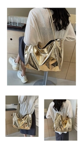 Detailed close-up showing the metallic cracked texture and slender strap of the gold tote bag
