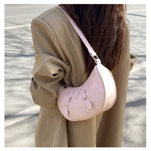 Detail of light pink half-moon shoulder bag showing silver rivets and smooth leather texture