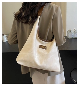 Détail d'un sac hobo beige avec lanières en cuir marron et étiquette de mode sur un mannequin
