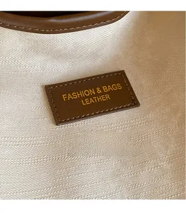 Détail de l'étiquette en cuir marron cousue avec texte mode sur sac bandoulière en toile