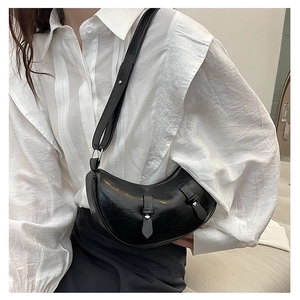 Detail of black crescent shoulder bag featuring glossy texture and silver metal buckles