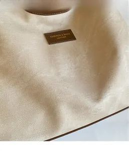 Vue macro détaillée de la texture du tissu sergé beige et du patch logo en cuir marron