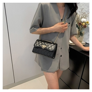 Classic black quilted crossbody bag with gold chain strap shown on a model
