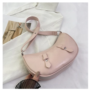 Detail of light pink crescent underarm bag with decorative buckles and silver rivets