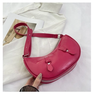 Detail view of pink crescent bag with glossy wax leather texture and buckle details