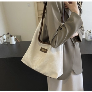 Détail du sac cabas minimaliste en toile avec finitions et anses en cuir marron foncé
