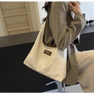 Sac fourre-tout crème chic avec bordure en cuir marron foncé, présenté sur un mannequin