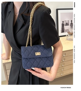Detailed shot of a blue quilted denim shoulder bag with a gold chain strap and turn-lock
