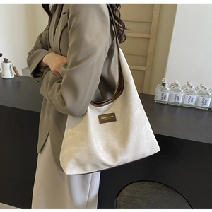 Détail du sac cabas en toile bicolore avec bordure en cuir marron et étiquette mode