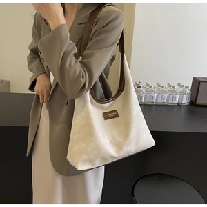 Détail de la couture contrastée et logo en cuir marron sur un grand sac cabas ivoire