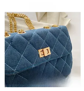 Macro shot of blue denim quilted bag with golden metal chain strap and twist lock