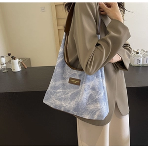Détail du sac cabas en toile tie-dye bleu clair avec brides et finitions en cuir brun