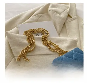 Detail of blue denim quilted bag featuring gold chain strap and metallic twist lock