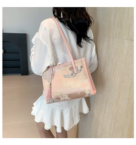 Detail of pink silk tote bag featuring exquisite floral embroidery and fringe tassel