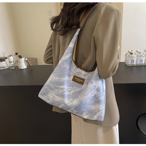 Détail du grand sac à bandoulière avec motif marbre bleu et finitions en cuir brun