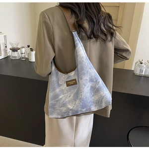 Détail du sac bandoulière tie-dye bleu clair avec bandoulière en cuir marron au café