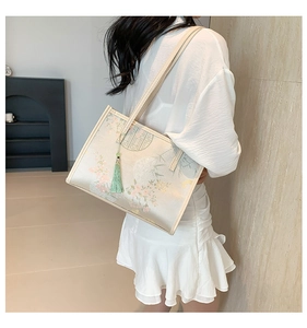 Detail of silk-texture cream tote bag featuring traditional Chinese floral and bamboo patterns
