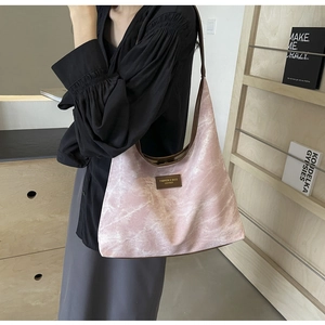 Détail du sac bandoulière à motif marbre rose avec logo en cuir marron et fine bride