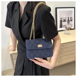 Detail of blue denim quilted crossbody bag with gold chain strap worn by a model