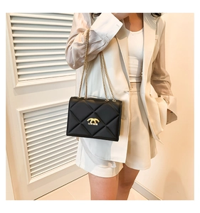 Close-up of black quilted leather shoulder bag with gold chain and brand logo