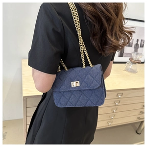 Gros plan du sac bandoulière en denim bleu matelassé avec chaîne dorée et fermoir